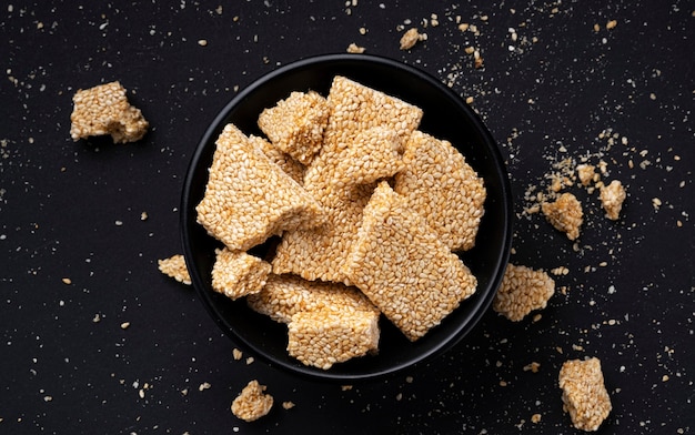 Sesame kozinaki in bowl on black background