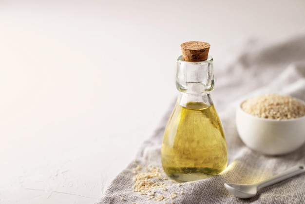 Sesame oil in a glass bottle and sesame seeds on the table. Copy Space