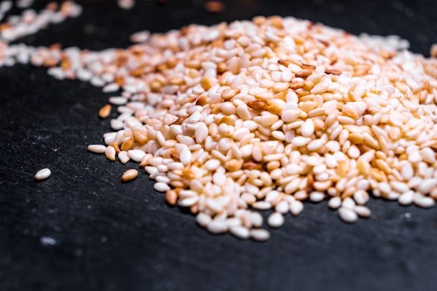 Sesame seeds on black stone background. close up