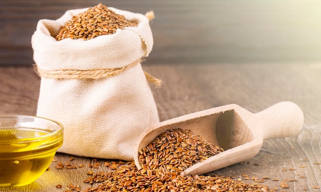 Sesame seeds in sack and bottle of oil on wooden rustic table on sunlight