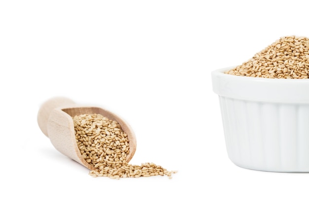 Sesame seeds in a wooden spoon and in a white bowl