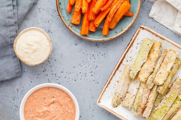 Set of baked season vegetable sticks of zucchini and carrots with sauce and hummus Vegetarian healthy food Flat lay top view