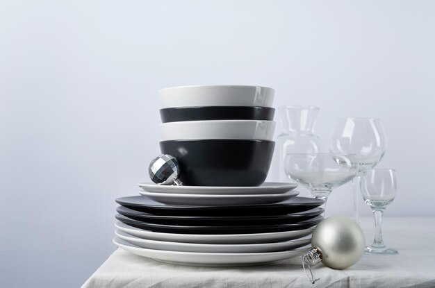 Set of black and white tableware with plates cutlery and glasses with holiday decorations on dining table copy space