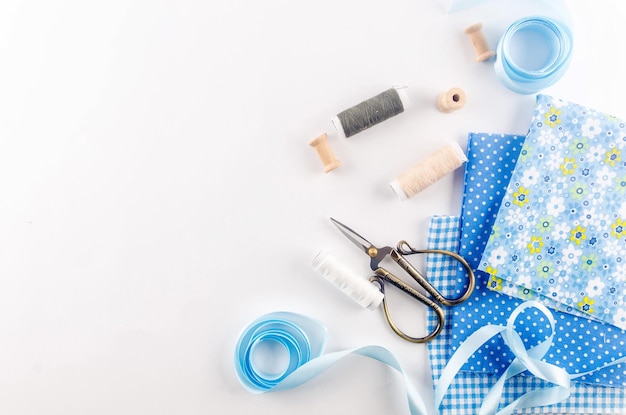 Set of blue sewing thread fabrics,  buttons and accessories on a white background. Flat lay composition with other sewing stuff.