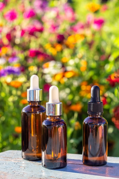 Set of brown glass dropper bottles with serum essential oil or other cosmetic product on bright floral background Natural Organic Spa Cosmetic Beauty Concept Mockup Front view