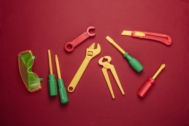 Set of children's toy work tools on red.