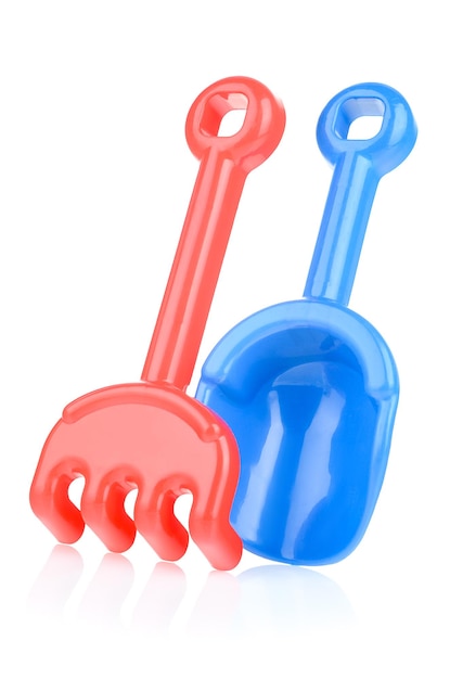 A set of children's toys for playing in the sandbox Colored rake and shovel made of plastic isolated on a white background closeup Early child development children's leisure concept