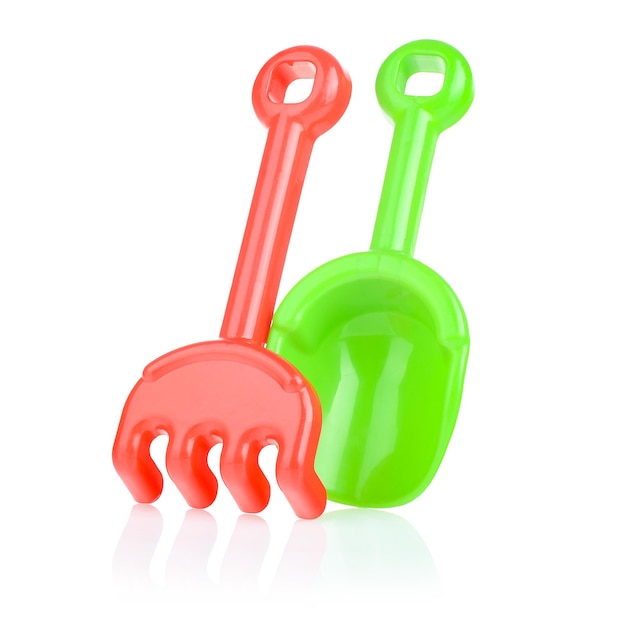 A set of children's toys for playing in the sandbox Colored rake and shovel made of plastic isolated on a white background closeup Early child development children's leisure concept