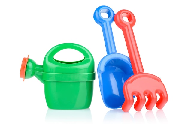 A set of children's toys for playing in the sandbox Colored rake shovel watering can made of plastic isolated on a white background closeup Early child development children's leisure concept