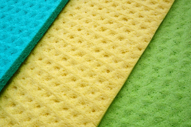 A set of cleaning wipes microfiber cloths or sponges for the kitchen three multicolored cloths Sponge fibers sponge texture pattern surface closeup background Green blue and yellow