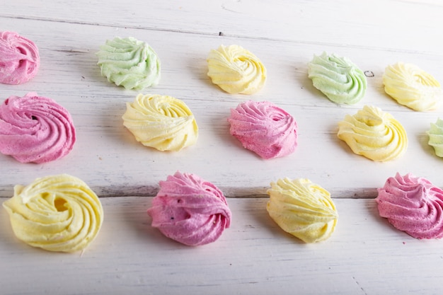 Set of colored meringues on white wooden background. geometric pattern.