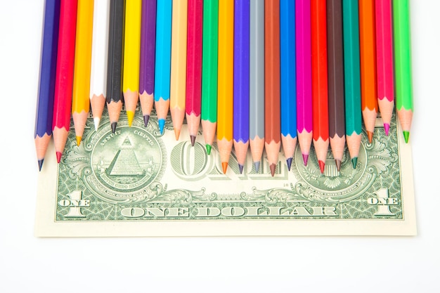 set of colored pencils for drawing on a dollar background. sales marketing