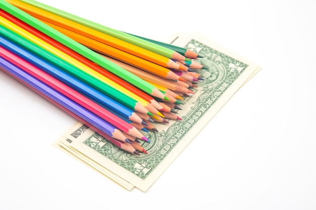 Set of colored pencils for drawing on a dollar background.