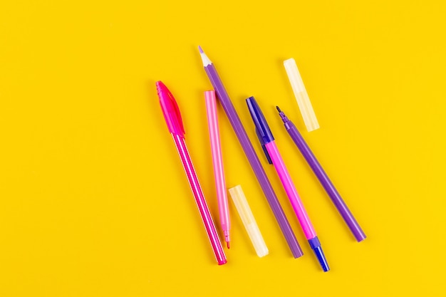 Set of colored pens on yellow paper background