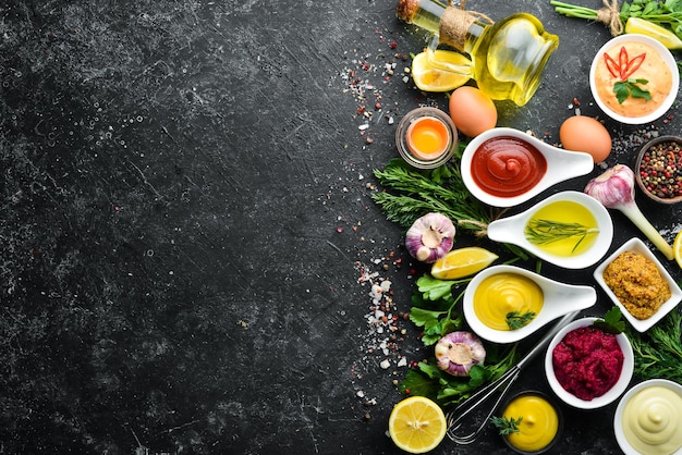 Set of colored sauces and spices on black stone background Traditional sauces for meat and fish