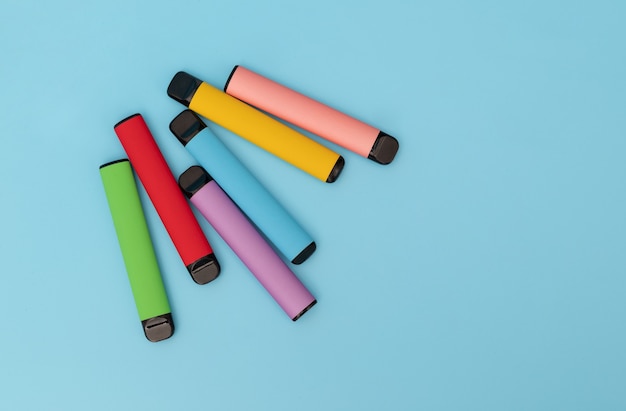 Set of colorful disposable electronic cigarettes on a blue background The concept of modern smoking