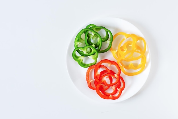 Set of colorful sliced bell pepper on plate on white Slices of red yellow and green bell pepper