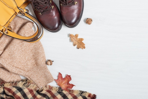 Set of comfort female warm clothes for autumn time top view on white wooden background