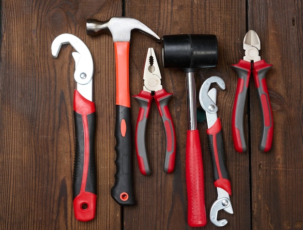 A set of construction tools on a brown wooden background top view Hammer pliers adjustable wrench