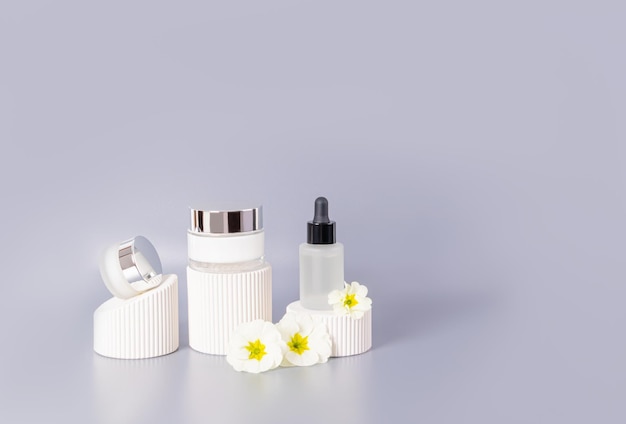 Set of cosmetic natural selfcare products on white embossed podiums on the grey background with begonia flowers Front view