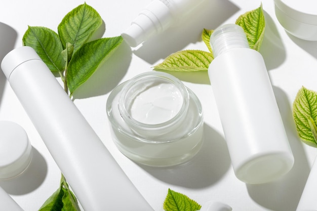 A set of cosmetic products in white tubes and with green leaves with empty space for labeling natural cosmetics for face and body skin care Moisturizing cream purifying mask