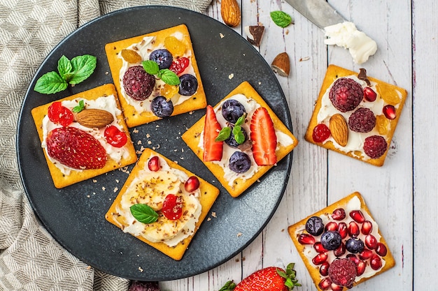 Set of crackers with various fruit close-up on black stone plate.