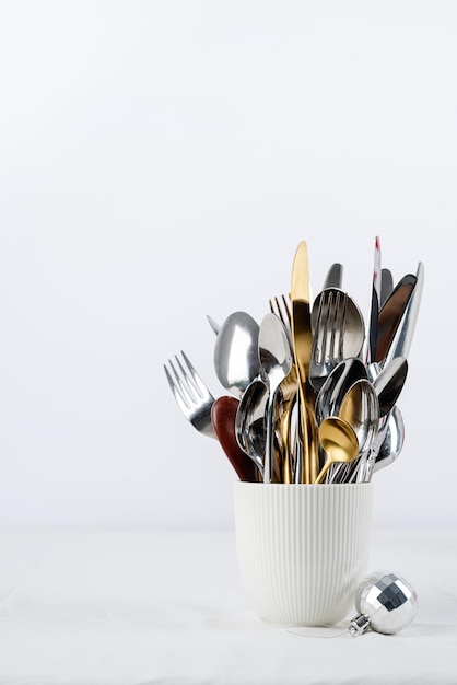 Set of cutlery of spoons knives and forks in cup with holiday decorations on dining table copy space