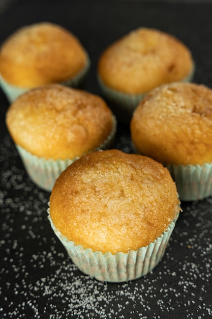 Set of delicious freshly baked cupcakes with sugar on top on a background