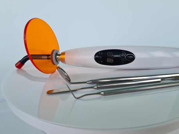 Set of dentures dental tools and curing light on table