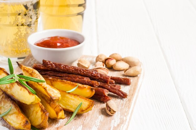 Set of different appetizers for beer are served on a cutting board and glasses with beer.