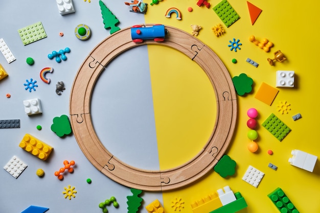 Photo set of different children's toys, round made of wooden rails, train, constructor on a yellow and blue surface