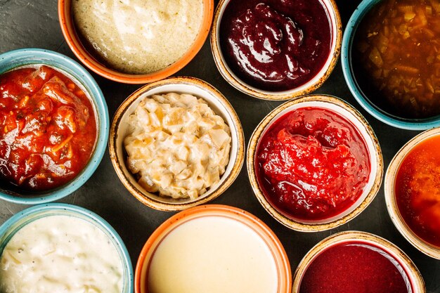 Set of different sauces on black wooden background