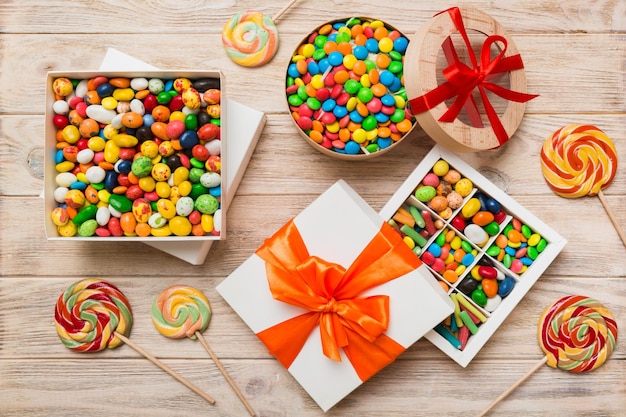 Set of different sweet candy in a paper box with a satin ribbon on a colored background Holiday concept