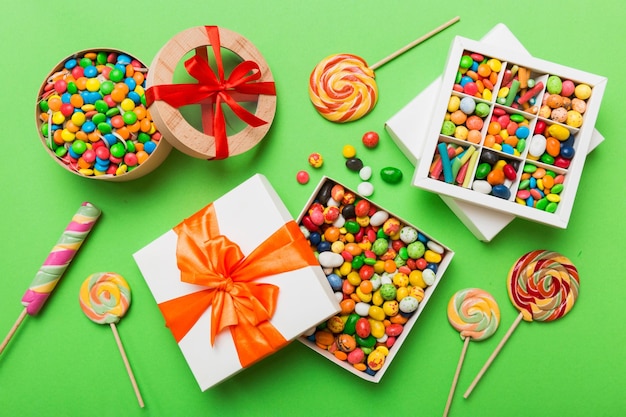 Photo set of different sweet candy in a paper box with a satin ribbon on a colored background holiday concept