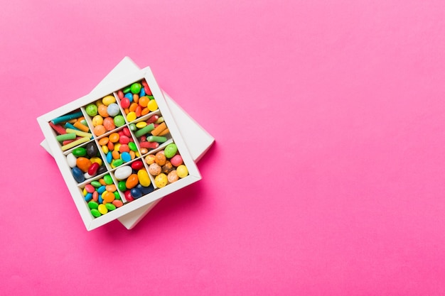 Set of different sweet candy in a paper box with a satin ribbon on a colored background Holiday concept