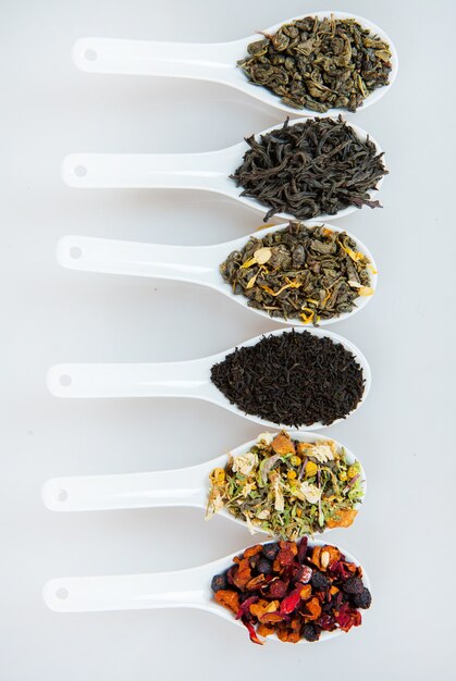 Set of different tea in bowls on white background