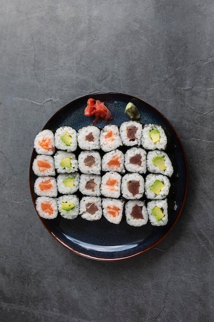 Set of different types of sushi rolls with salmon tuna and avocado on a rustic backgroundVertical view