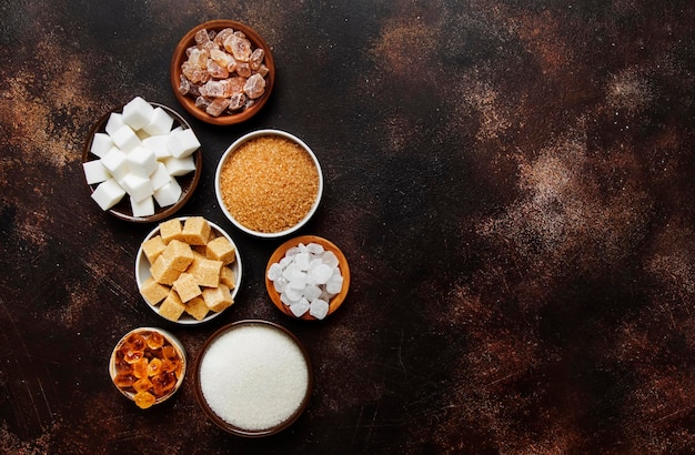 Set of different white and brown sugar in assortment dark background top view