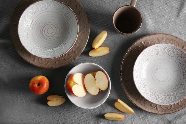 Set of dinnerware and fruits on tablecloth background