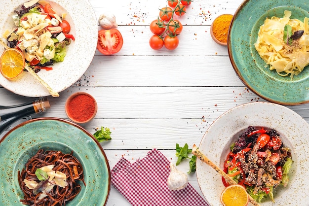 A set of dishes Pasta with parmesan cheese and vegetable salad and blue cheese Top view Free space for your text On a wooden background