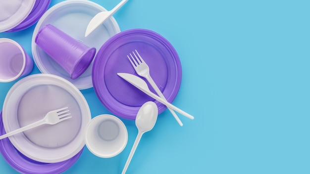 A set of disposable, lilac and white, plastic utensils. Blue background, copy space. The concept of