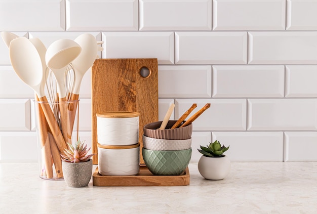 Set of ecofriendly utensils on a light kitchen countertop against a white brick wall with a copy of the space Front view Eco style