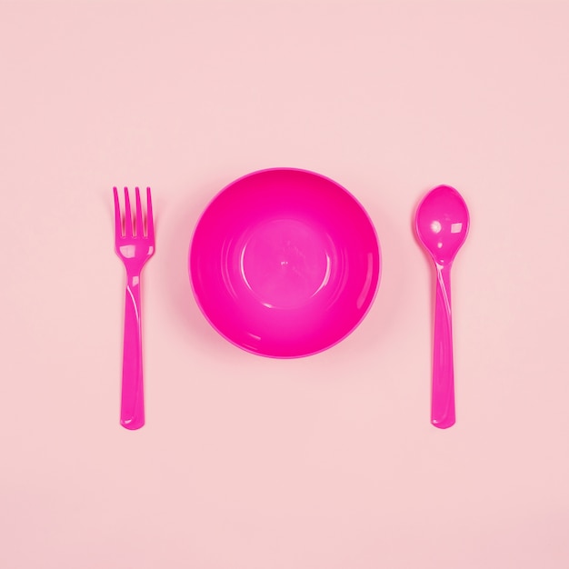 Set of empty pink plastic tableware bowls, spoons and forks