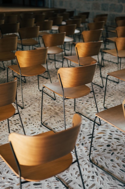 Set of empty wooden chairs lined up before an event in an ancient church or castle with medieval flo