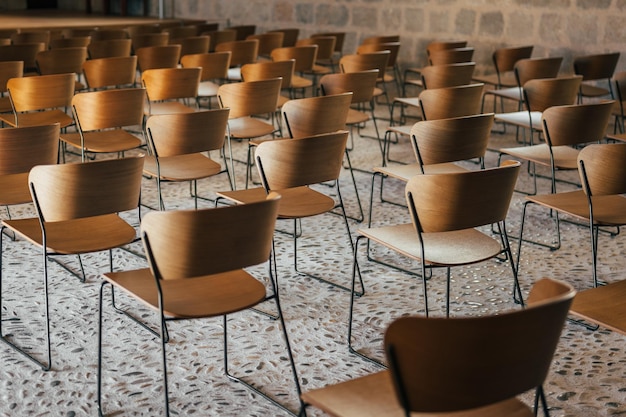 Set of empty wooden chairs lined up before an event in an ancient church or castle