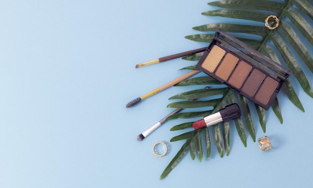 Set of female cosmetics with palm branch on a blue background