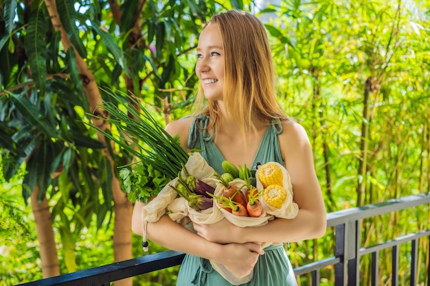 Set of fresh vegetables in a reusable bag in the hands of a young woman Zero waste concept