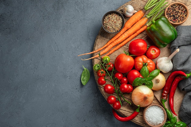 A set of fresh vegetables and spices for cooking a vegetable dish on a gray-blue background. Healthy food. Top view.