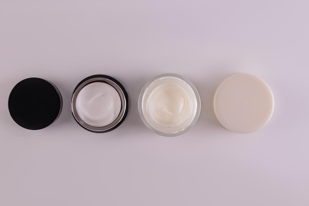 A set of glass jars with cosmetic cream of different colors for face and body skin care Design packaging Product presentation Top view mockup