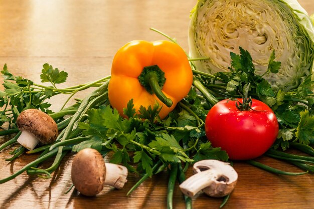 Set of good natural products with fresh cabbage, yellow pepper, red tomato, mushrooms, onion and parsley on the table